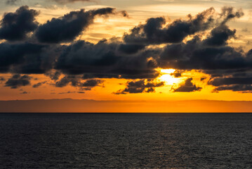 Fototapeta premium Distant mountain outlines along the Chilean coast illuminated by a vivid orange sunrise sky.