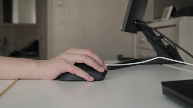 Ergonomic workspace with computer device. Precise hand operation on computer mouse with ergonomic setup scene. Minimalist home office with hand navigating wireless mouse