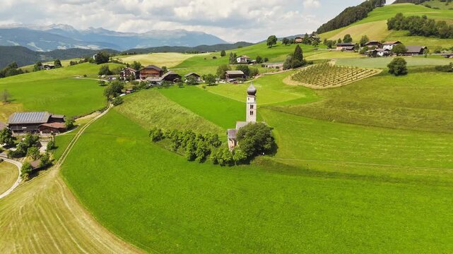 Stone Church of Saint Valentine near farm buildings and fields, aerial view. Cultural heritage within a rural area
