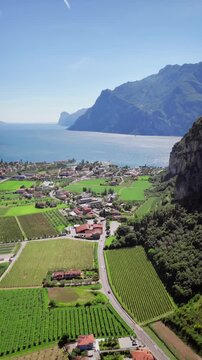 Wide drone shot of Torbole between water and cliffs on the edge of Lake Garda