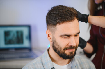 Obraz premium Trichologist examining man's hair scalp for baldness treatment