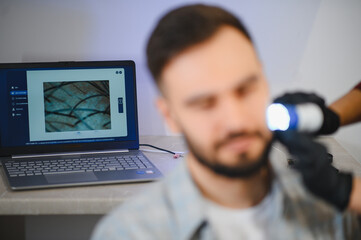 Man getting trichology scalp analysis with laptop