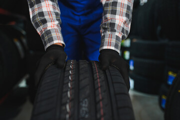 Fototapeta premium Mechanic holding new tire in auto service shop