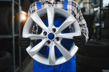 Car mechanic holding new alloy wheel rim