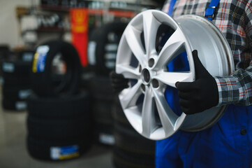 Auto mechanic holding car alloy wheel rim