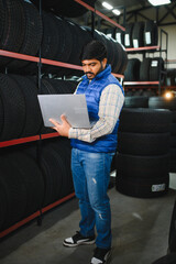 Indian man checking inventory on laptop in tire shop