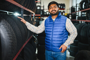 Mechanic smiling, checking car tires in service center store © Serhii