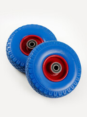 Two wheels from a garden cart on a white background. Blue rubber, red disc.