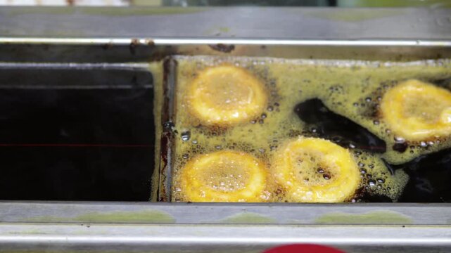Mini donuts fry in hot oil at a bakery