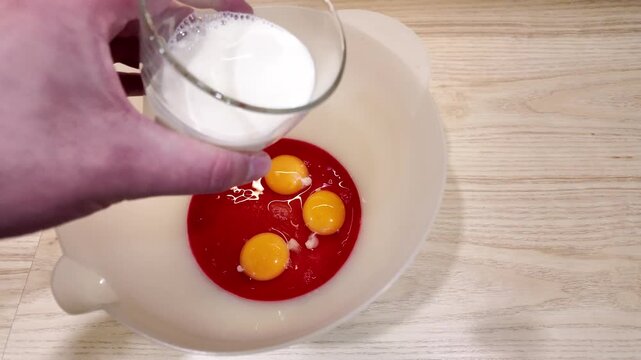 Eggs in bowl baking ingredients food preparation. Eggs sit in a white bowl with red liquid, likely pomegranate juice, for a dessert recipe