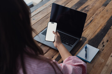 Close view of a woman holding a phone with a white screen at her workplace, highlighting copy space for e-commerce, fintech solutions, and online service applications in a professional environment