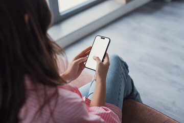 Close up shot of young female relaxing indoors at home holding mobile phone with blank screen for...