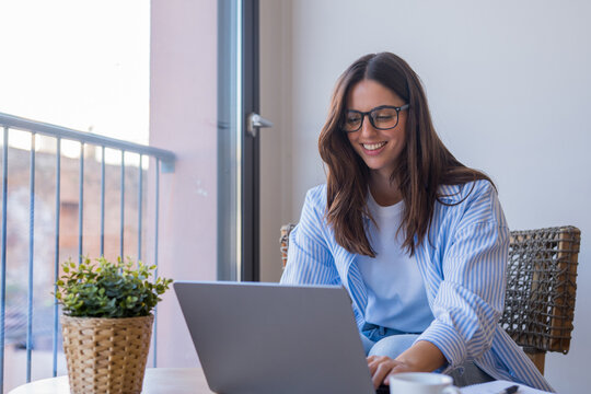 Successful virtual teamwork. Laughing gen z girl remote employee blended learning student communicate by videocall via notebook sit at table in cozy coworking space collaborate on online group project