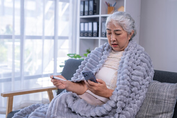 Elderly woman measuring temperature using smartphone for telehealth