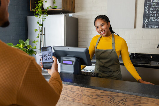 African American barista and customer scanning QR code at coffee shop terminal, copy space
