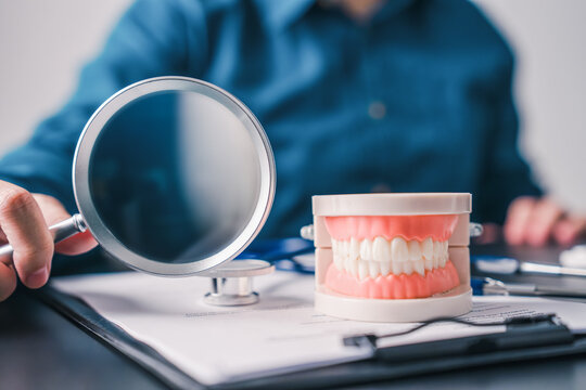 Professional dental checkup concept with tooth model and magnifying glass on clinic desk representing preventive care precision diagnosis and healthcare planning