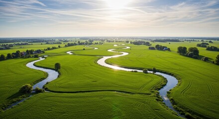 Serpentine River Meandering Through Lush Green Meadow Under Sunny Sky.