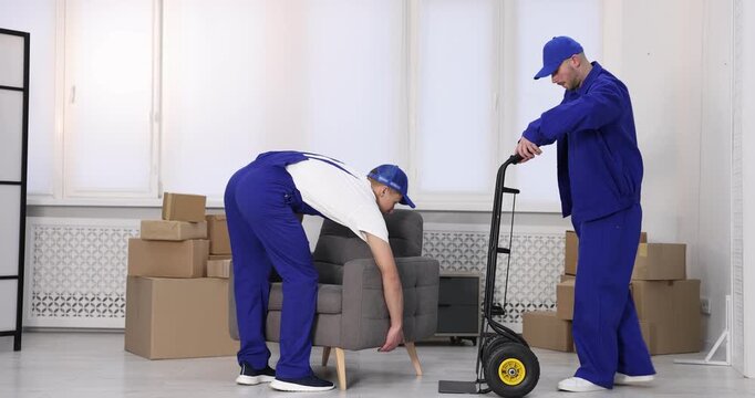 Two mover service workers carrying armchair indoors
