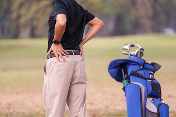 Rear view of golf player holding his lower back cause physical injure