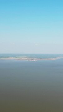 Aerial view of the expansive Baray Occidental reservoir with calm water and distant shoreline under a clear blue sky. Tranquil natural landscape with minimal human presence.