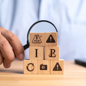 Magnifying Glass Examining Wooden Blocks with IAB and Warning Symbols.