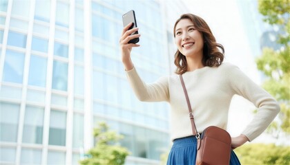 オフィス街でスマートフォンを掲げ笑顔を見せる女性