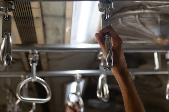 Close-up of a commuter gripping a metal handle inside a Mumbai local train, showing shiny steel grips, public transport, balance, movement and daily urban travel in India&rsquo;s bustling rail network.