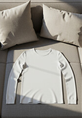 Clean white long-sleeve t-shirt displayed flat on a modern gray sofa with pillows for product design mockup concept and casual apparel advertising