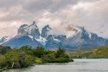 Jagged granite peaks of the Paine Massif tower above a lake and windswept vegetation in Torres del Paine National Park, Patagonia, Chile. © ZL Visuals