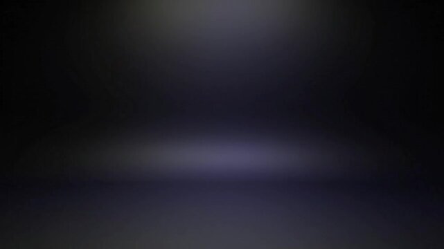 Dark room with a spotlight shining down on the floor creating a gradient of light and shadow