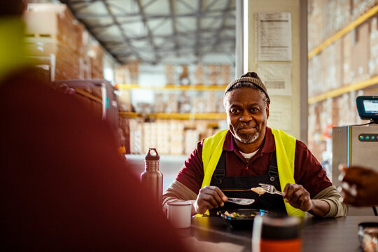 Smiling warehouse worker eating lunch during break