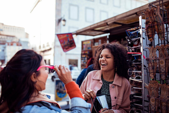 Two friends trying sunglasses at an outdoor city market