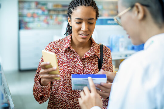 Woman consulting pharmacist about medication in pharmacy