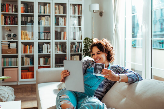 Expectant mother showing ultrasound during video call at home