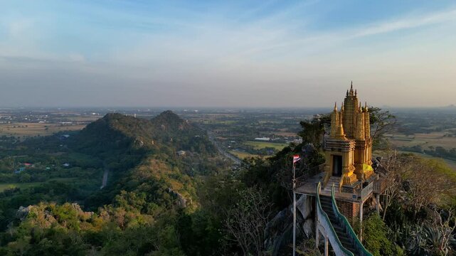 A statue of Jesus standing on a hill in Khao Khup Pha Sawan area, Pak Tho district, Ratchaburi province, Thailand, with houses and factories visible.