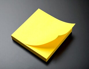 Stack of bright yellow paper notes with a curled corner on a dark, glossy surface