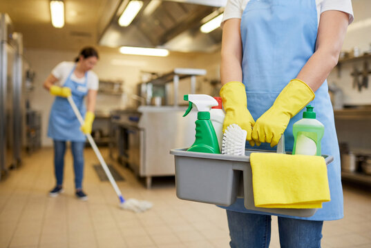 Female janitor holding cleaning caddy in commercial kitchen