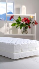 Stacked white mattresses with a shelf of flowers in a bright airy room setting