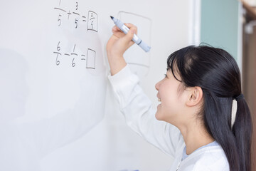 ホワイトボードに分数を書き込む小学生