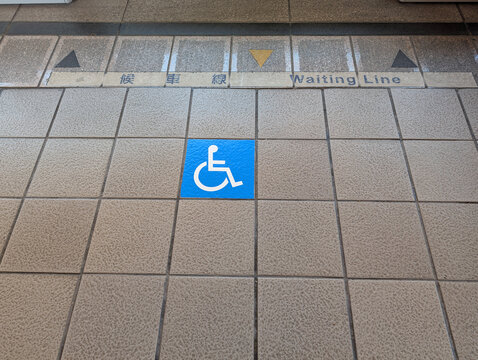 Disabled passenger priority sign on the floor at a modern MRT station entrance.