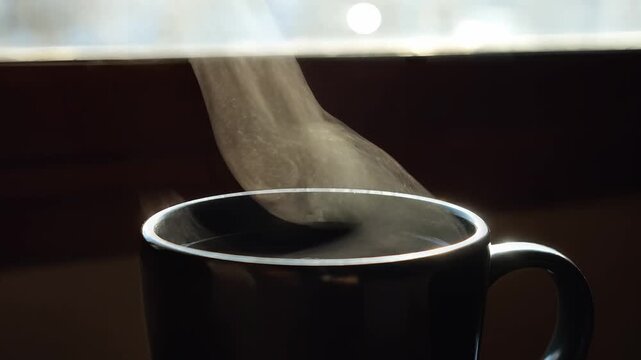 Cinematic close-up of steaming hot coffee in a dark mug with swirling steam rising and catching soft light, symbolizing warmth, relaxation