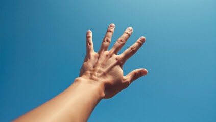 A close-up of an outstretched hand reaching toward a clear blue sky, symbolizing hope and aspiration