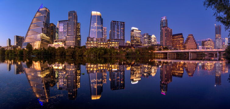 Austin at Dusk - A panoramic dusk view of glittering modern skyscrapers reflecting in calm Lady Bird Lake at Downtown Austin, Texas, USA.