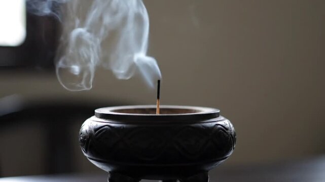 Incense rising from a bokor incense burner, a close up view of the smoke and fragrance filling the serene environment.