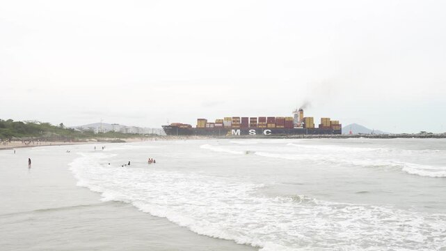 Container ship MSC JULIE sails past beachgoers in Atalaia, Itajai, Brazil