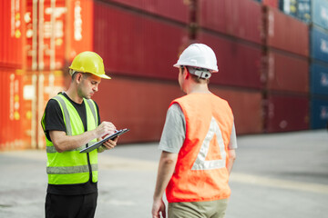 Warehouse team discussing shipment status during on site supervision at freight terminal. Industrial transportation and global trade theme.