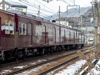 Obraz premium 雪が積もる住宅地を走る能勢電鉄の5100系電車