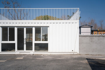 Obraz premium White shipping container converted into a modern minimalist building exterior under clear blue sky