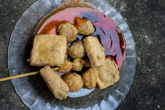 Portrait of Indonesian somay and street meatballs placed on a cement floor, capturing authentic local street food atmosphere and texture.