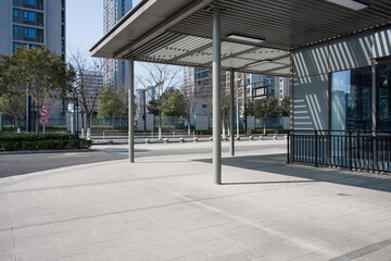 Modern urban bus shelter with empty plaza and surrounding high-rise buildings under clear daylight